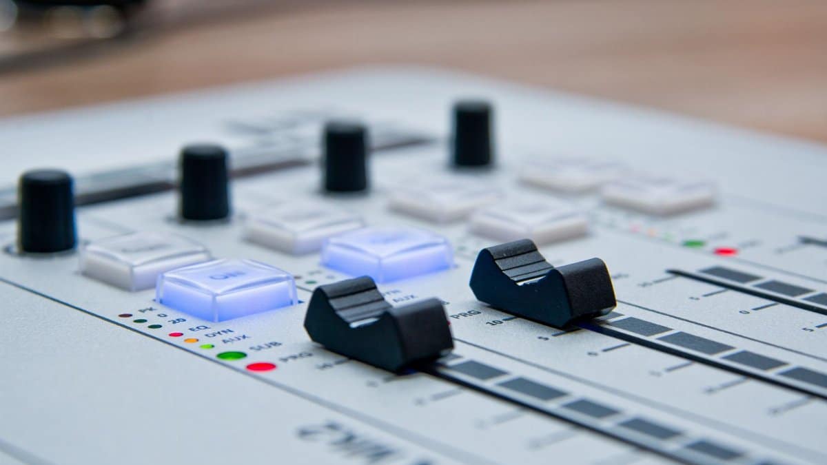 Detailed view of a professional sound mixer with glowing controls and sliders for audio production.