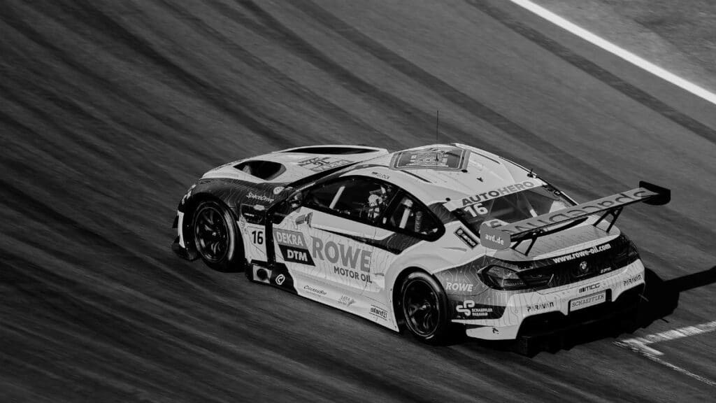 A dynamic black and white photo of a high-speed race car on a track, capturing motion and speed.