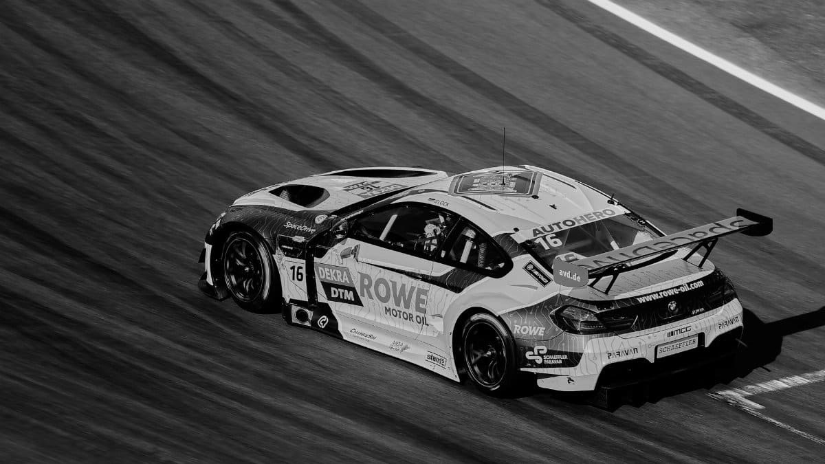 A dynamic black and white photo of a high-speed race car on a track, capturing motion and speed.