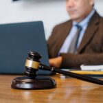 Crop concentrated Asian male judge in formal clothes sitting using modern netbook while working in law office