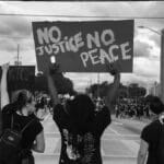 A group of protesters gather in the city for a human rights rally, holding signs.