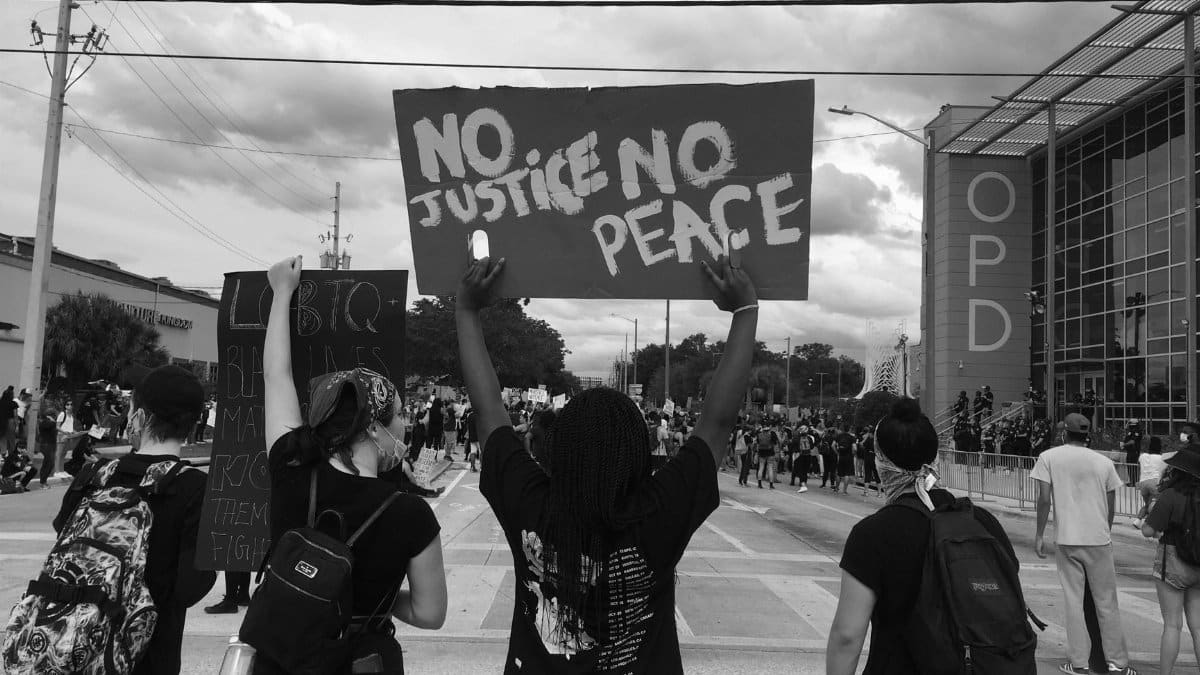 A group of protesters gather in the city for a human rights rally, holding signs.