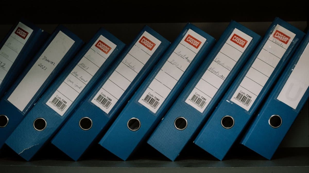 Neatly arranged blue office binders labeled with dates and names for organized storage.