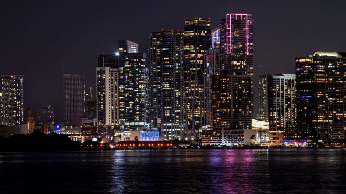 A stunning view of Miami's illuminated skyline reflecting on water at night.