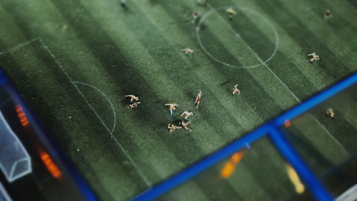 A top-down view of a miniature soccer match featuring tiny figurines on a football field.
