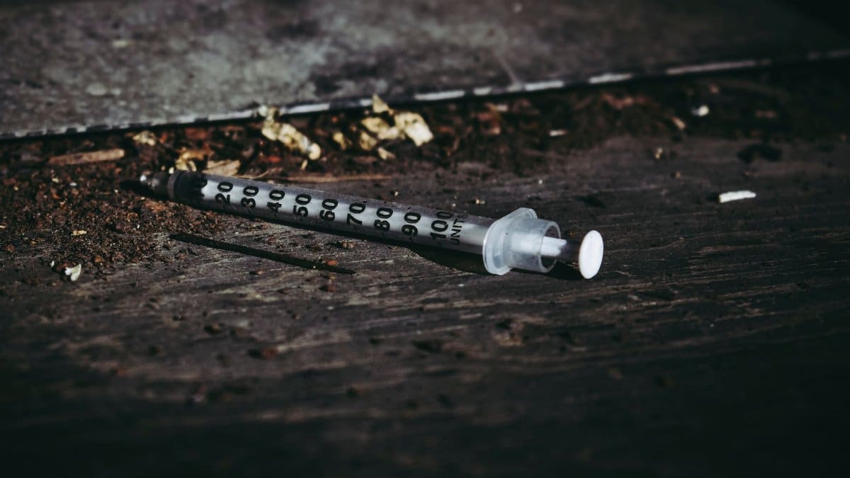 Close-up of a discarded syringe on a rough surface highlighting addiction issues.