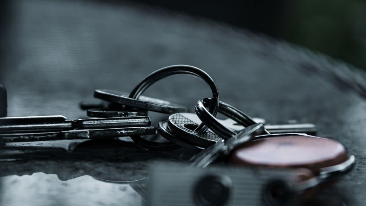 A dramatic close-up of metal keys on a reflective surface, capturing a moody and conceptual still life.