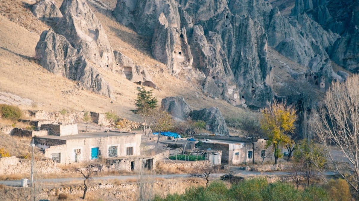 Scenic view of a remote village nestled among rocky hills in a vibrant autumn setting.