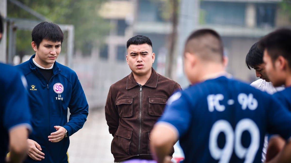 Football players gather for a team discussion on a soccer field in Hanoi, Vietnam.