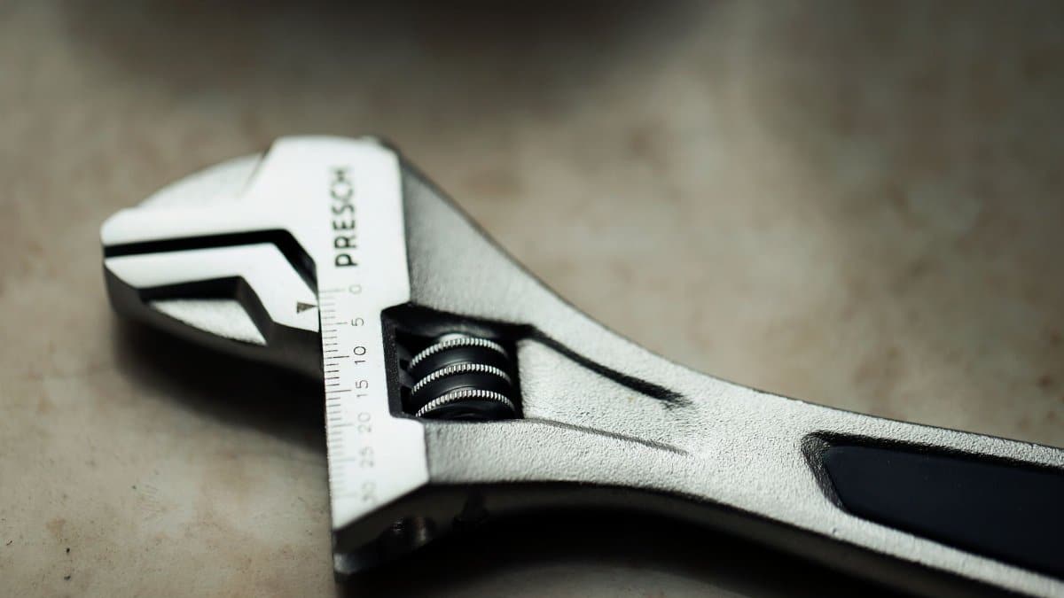 Detailed macro shot of a metallic adjustable wrench placed on a textured surface.