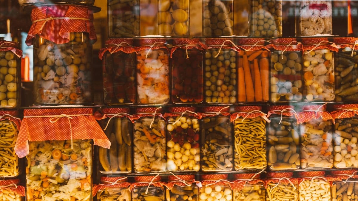 Rows of colorful preserved vegetables in glass jars, showcasing variety and abundance.