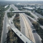 Aerial perspective of a complex highway intersection with moving vehicles during daytime.