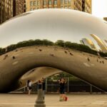 The iconic Cloud Gate sculpture reflecting downtown Chicago's skyline at sunset in Millennium Park.