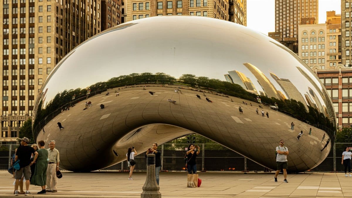 The iconic Cloud Gate sculpture reflecting downtown Chicago's skyline at sunset in Millennium Park.