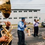 Black people in casual clothes standing together with musical instruments and playing jazz on street near road