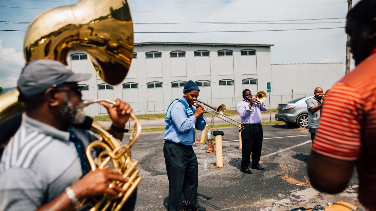 Black people in casual clothes standing together with musical instruments and playing jazz on street near road