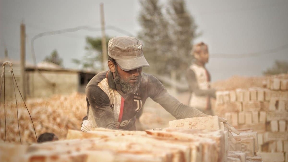 Men working with bricks in a dusty environment, focusing on manual labor and construction.
