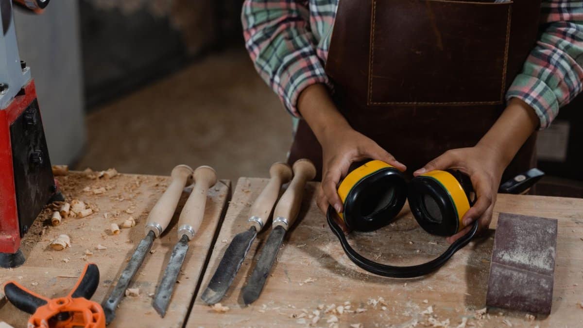 A woodworker prepares tools and equipment in a dusty workshop, demonstrating craftsmanship.