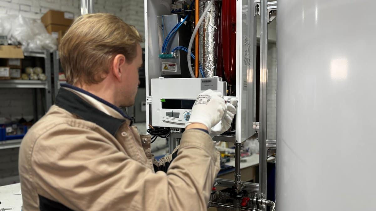 Technician installing or repairing a heating system in an indoor workshop setting.