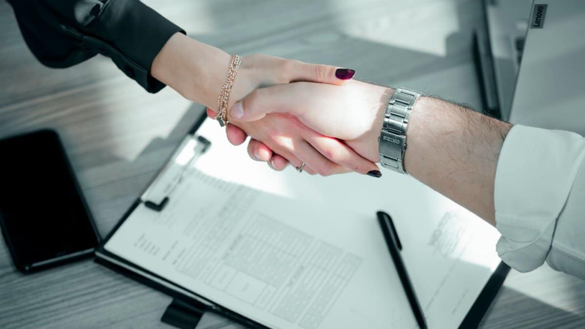 Close-up of a professional handshake over a contract, symbolizing a successful business deal.