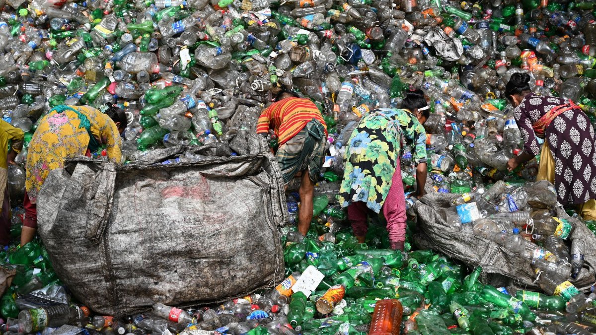 Workers sorting plastic waste at a landfill in Chattogram, Bangladesh. Environmental and recycling theme.