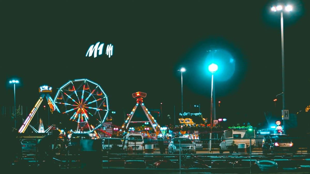 Vibrant nighttime scene of an illuminated amusement park with a ferris wheel and rides.