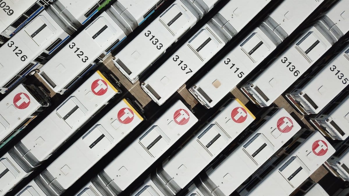 Drone shot of white buses parked at a transit hub, seen from above.