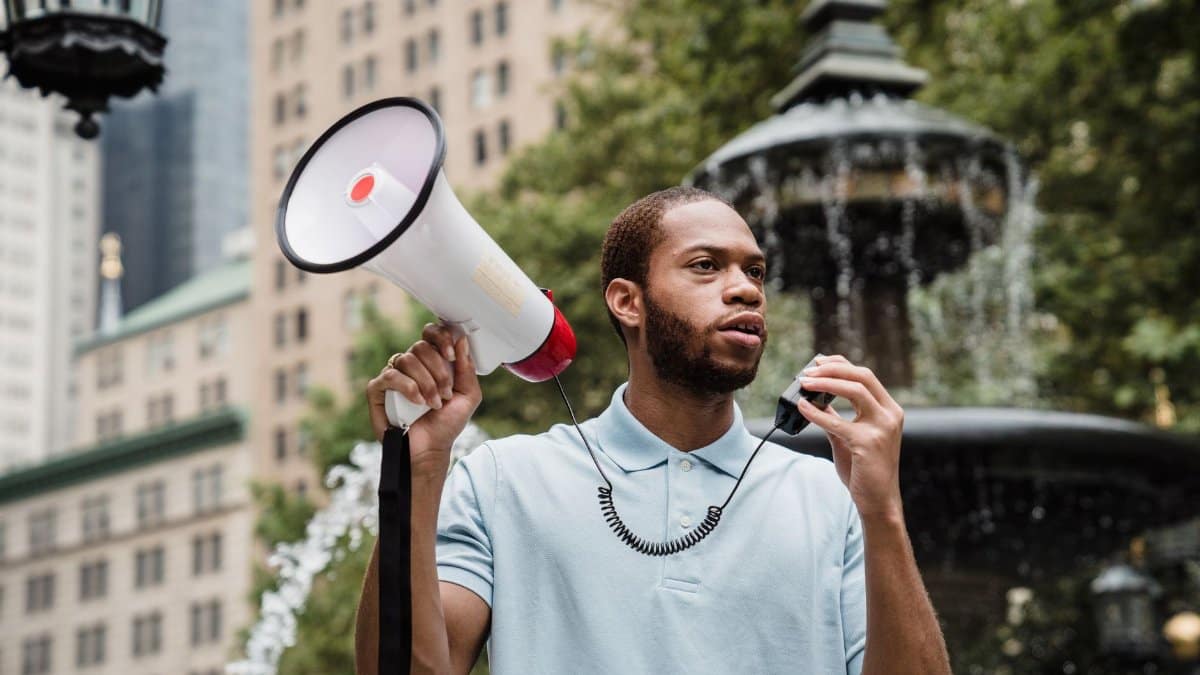 Young man holding megaphone in city protest, emphasizing nonviolent activism.