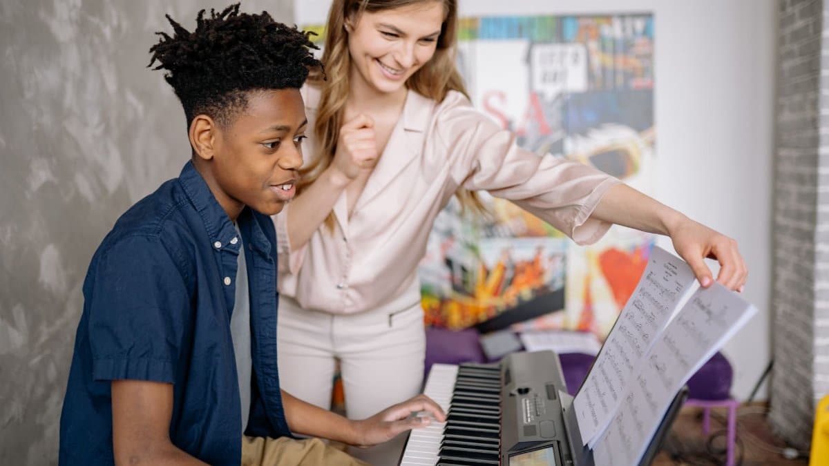 A young boy receives piano lessons from a dedicated teacher at home, fostering musical skills.
