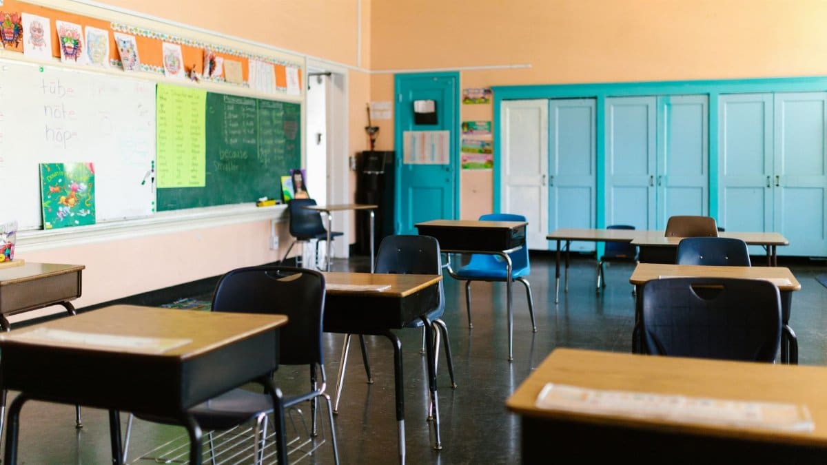 Bright and colorful empty classroom with desks, blackboard, and educational materials.