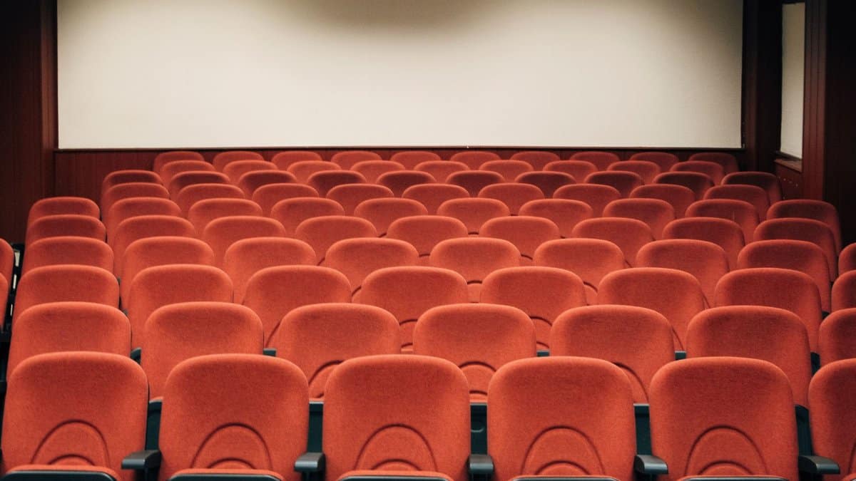 A spacious theater with empty red seats and a large screen, ready for the next audience.