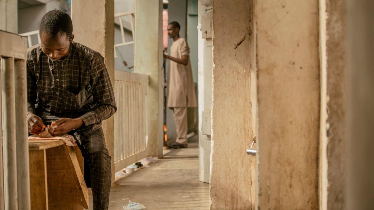 A focused craftsman works in a corridor in Nigeria, showcasing traditional craftsmanship.