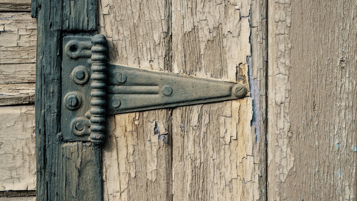Detailed view of a rustic metal hinge on a weathered wooden door in Boise, ID.