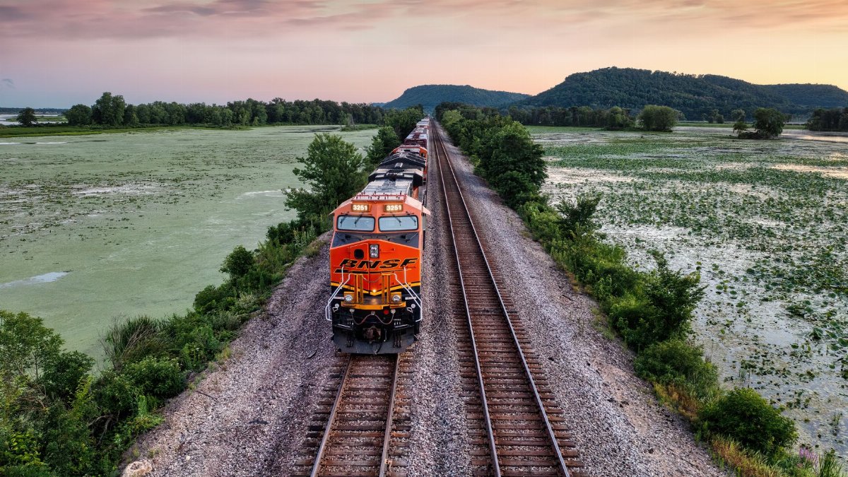 Aerial view of a freight train on a railway through wetlands at sunset near Alma, Wisconsin.
