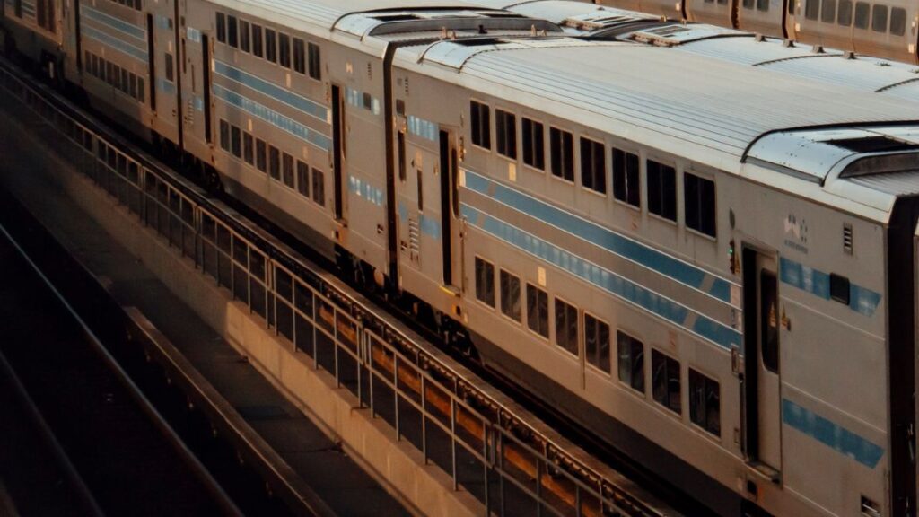 A cinematic view of double-decker trains in an empty New York rail yard at dusk.