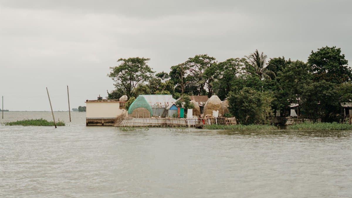A rural island with simple structures surrounded by rising floodwaters.