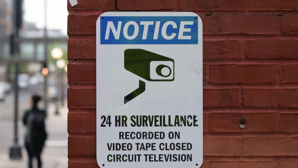 Close-up of a surveillance notice on a brick wall, urban setting.