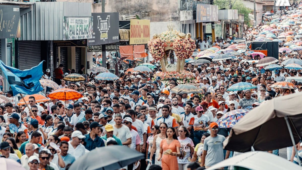 A lively street parade with a large crowd and colorful umbrellas in a bustling city environment.