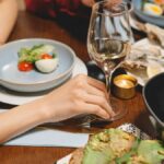 A close-up of a dining table with white wine and seafood dishes, creating a warm ambiance.