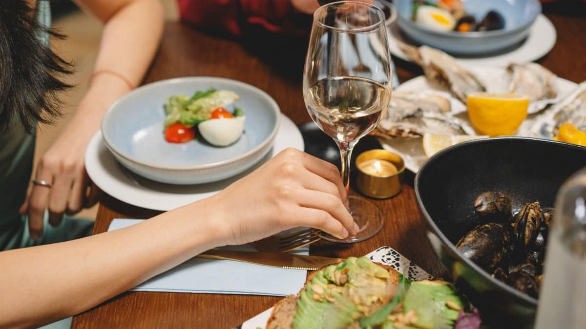 A close-up of a dining table with white wine and seafood dishes, creating a warm ambiance.