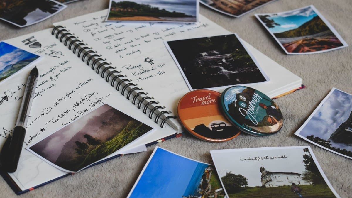 Travel diary surrounded by printed photos and a pen, capturing memories creatively.