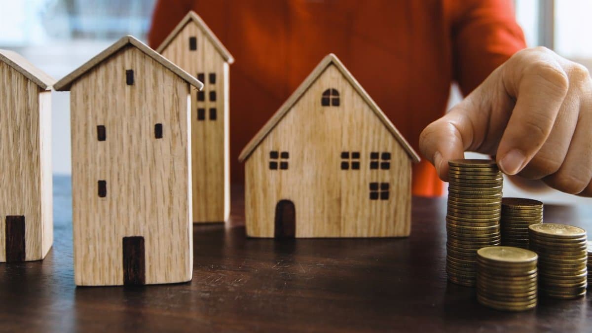 Planning investments with stacked coins and model houses on a table.