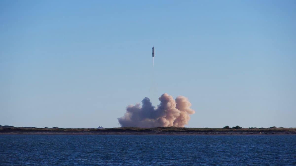 A rocket launch with smoke trails over South Padre Island, viewed across the ocean.