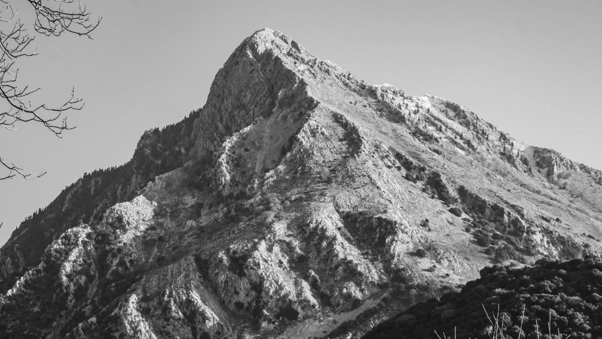 Dramatic black and white photograph of a rugged mountain peak.