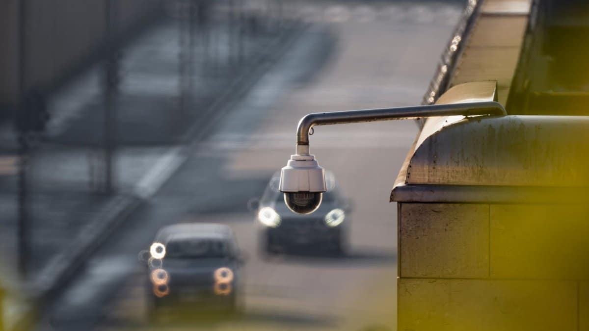 CCTV camera overlooking a busy street with cars in motion, capturing urban surveillance.