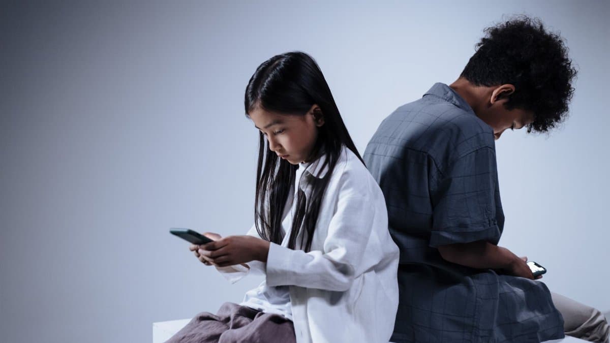 Two teenagers engrossed in their smartphones, highlighting digital connection and youth lifestyle.