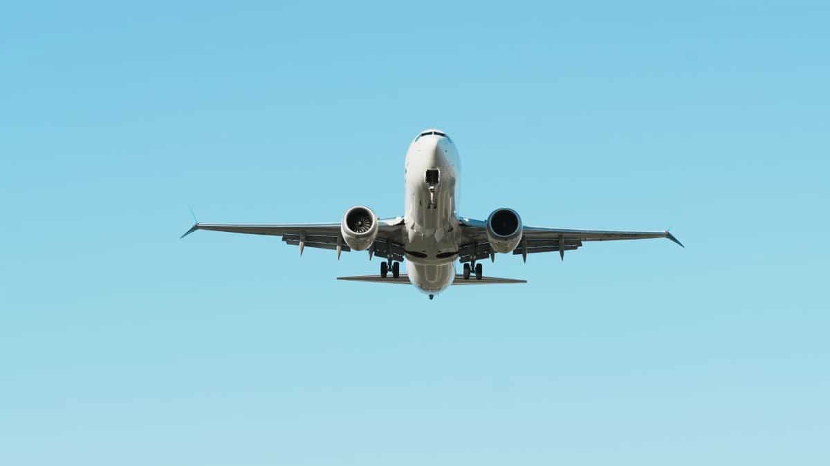 A front view of an airplane in flight against a clear blue sky, showcasing aviation.