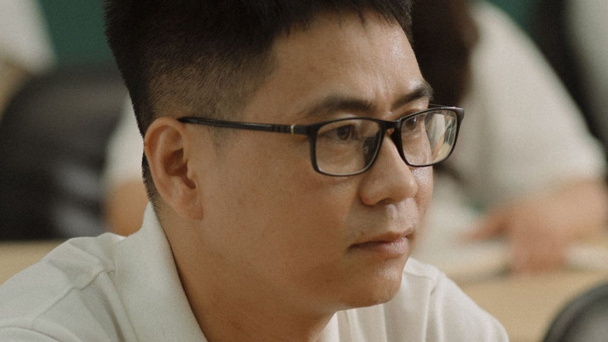 A focused man wearing eyeglasses looks ahead thoughtfully.