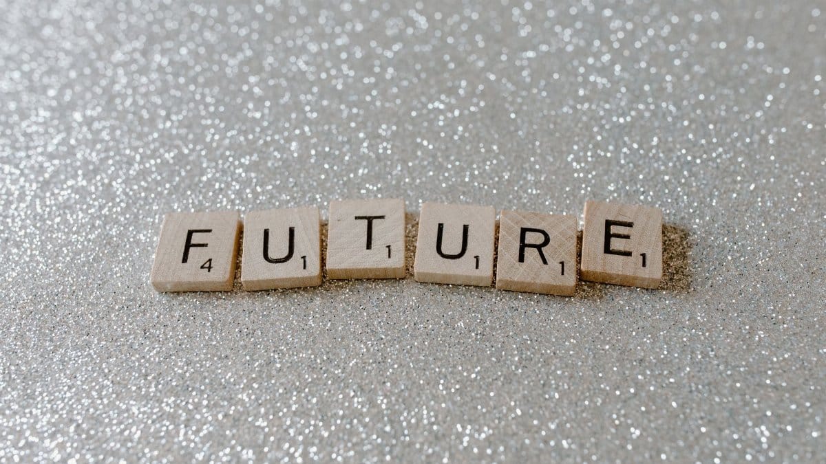 Wooden Scrabble tiles spell 'Future' against a shimmering glitter background.