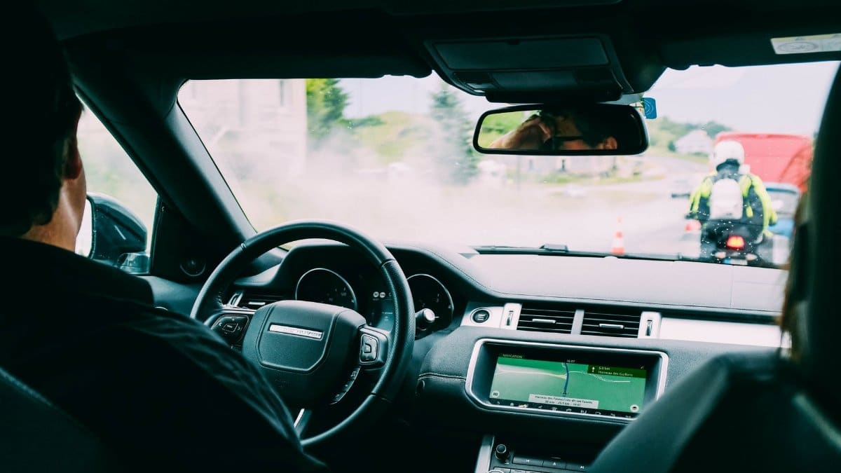 Interior view of a car with GPS navigation and traffic ahead, showcasing urban transportation.